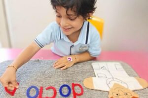 Young child at Starshine Montessori preschool engaging in a hands-on letter recognition activity with a doctor-themed learning mat, promoting early literacy and role-play development.