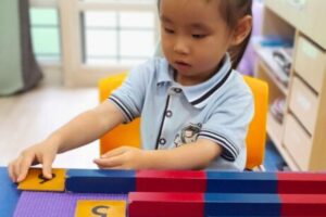 Young child at Starshine Montessori engaged in hands-on math activity with Montessori number rods and cards, developing early numeracy skills.