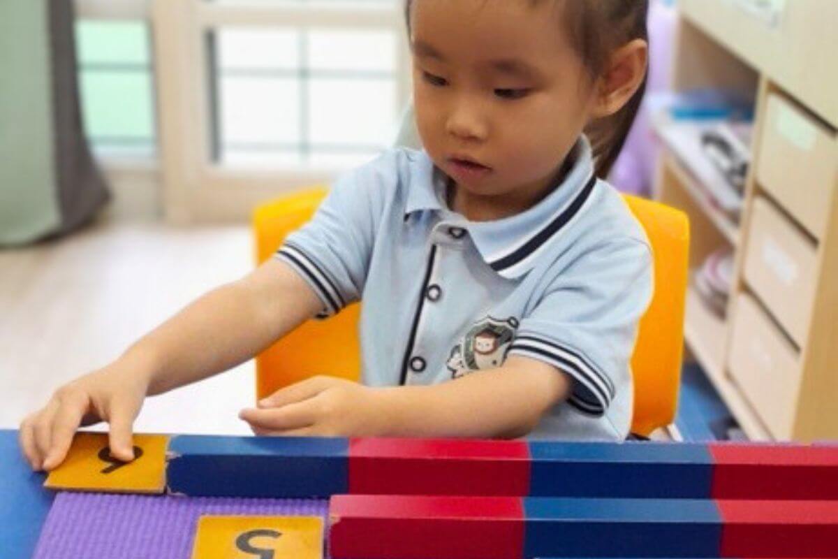 Young child at Starshine Montessori engaged in hands-on math activity with Montessori number rods and cards, developing early numeracy skills.