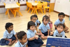 Young children in uniform attentively listening to a story during circle time at Starshine Montessori preschool classroom.