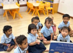 Young children in uniform attentively listening to a story during circle time at Starshine Montessori preschool classroom.