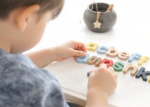 Toddler learning the alphabet using colorful wooden letters in a Montessori-inspired hands-on activity.
