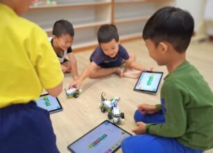 Children engaging with educational robots and tablets during an interactive AI and coding activity in a classroom at Starshine Montessori preschool.