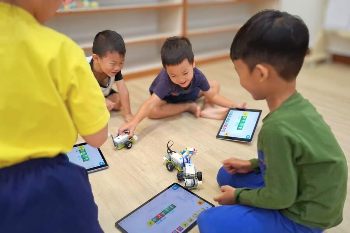 Children engaging with educational robots and tablets during an interactive AI and coding activity in a classroom at Starshine Montessori preschool.