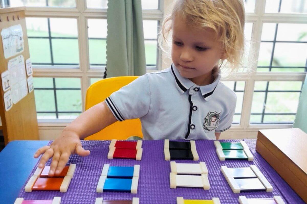 Preschool child at Starshine Montessori engaging in a colour tablet matching activity to develop visual discrimination and concentration.