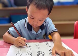 Preschool boy at Starshine Montessori focused on writing Chinese characters during bilingual language development activity.