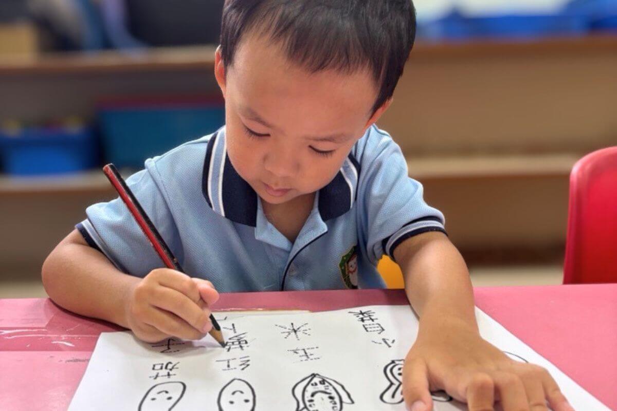 Preschool boy at Starshine Montessori focused on writing Chinese characters during bilingual language development activity.
